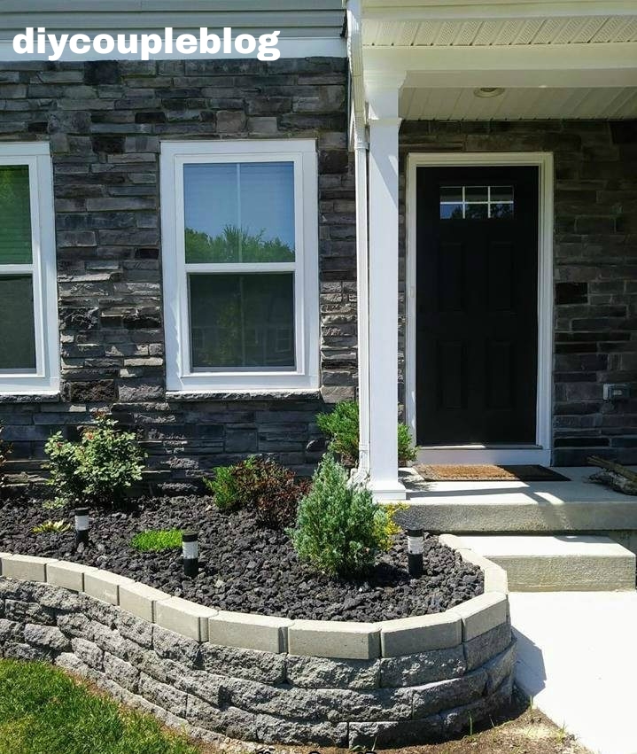 retaining wall with concrete blocks and lava rock landscaping on the top for a modern flower bed design