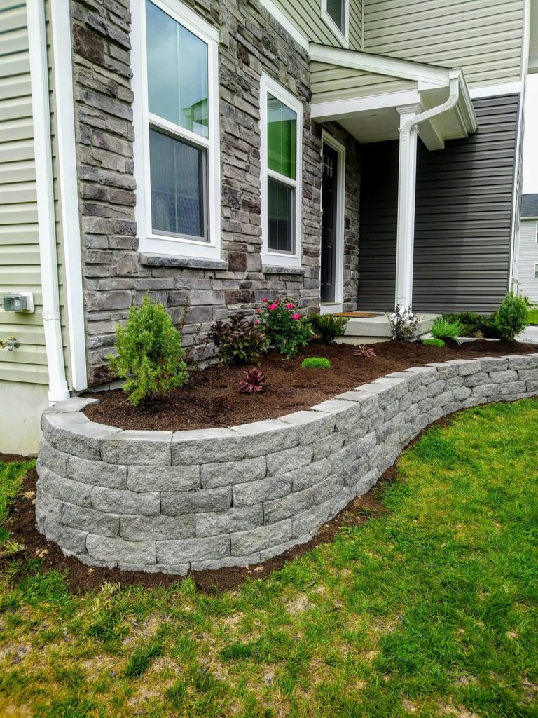 diy retaining wall in front of our house with some add dirt and perennial flowers