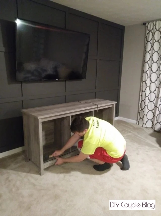 homeowner putting new TV stand together to change the whole look of the space keeping it clean with no cord wires