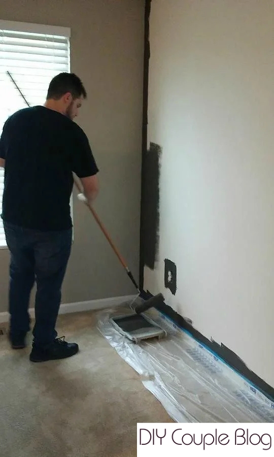Roller applying dark gray paint to accent wall. 