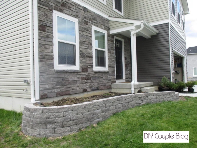 Modern raised flower bed construction enclosed by a smooth gray stone wall