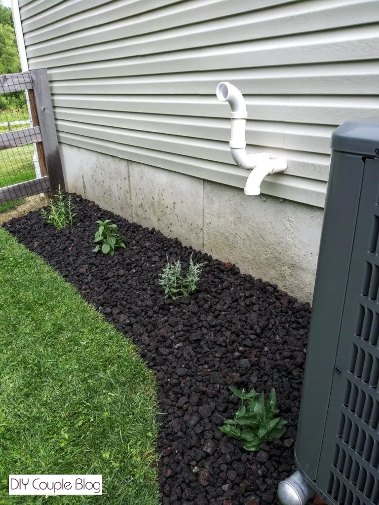 black lava rock landscaping around air conditioner unit