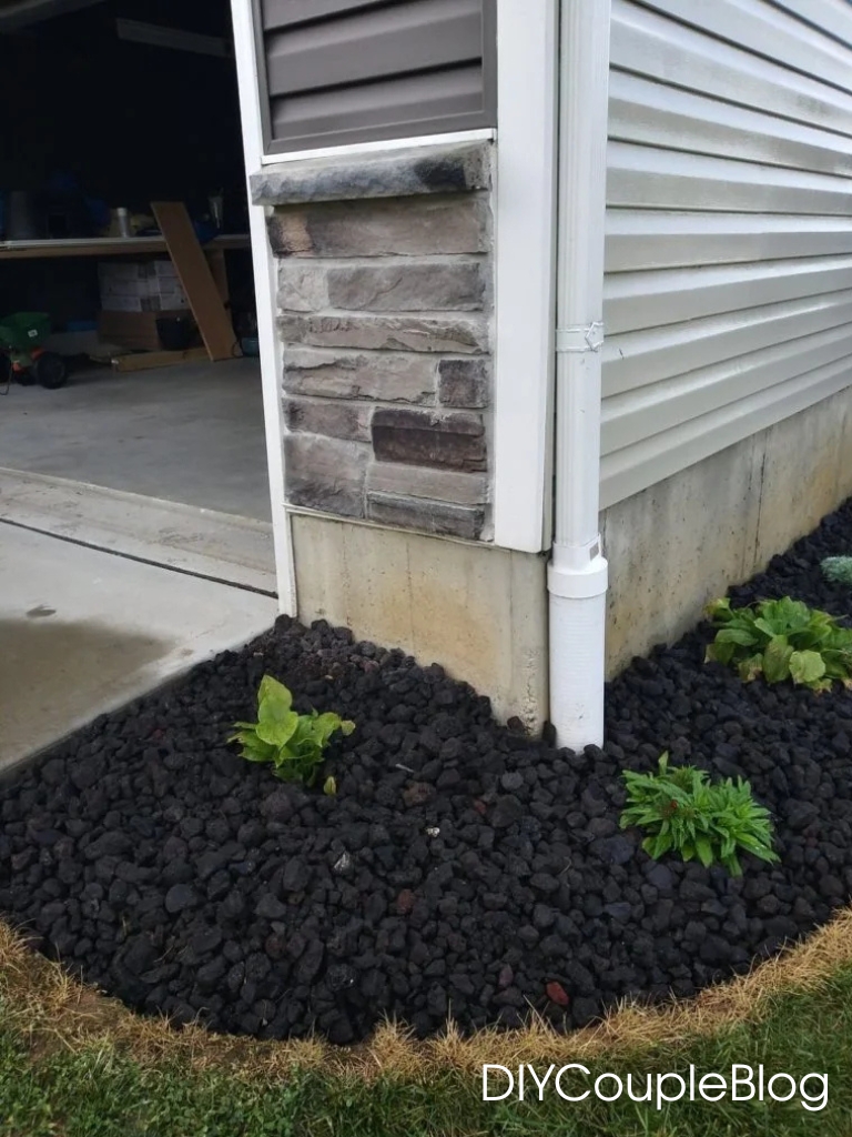 a photo of the garage side of the house with adding a flower bed wrapping around the side of house