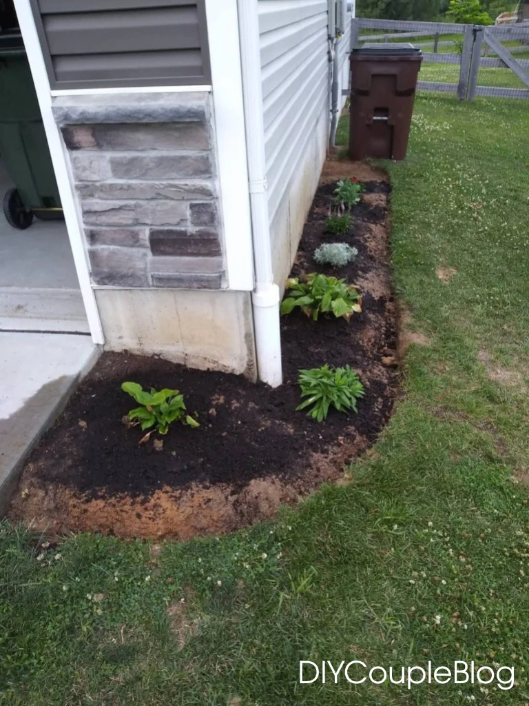 planting flowers on the side of the house adding miracle gro soil and moisture control to help them thrive