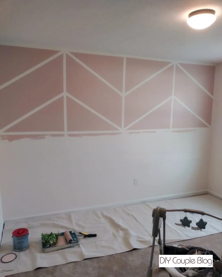 nursery wall with a fun pink paint color with white chevron design on the upper half
