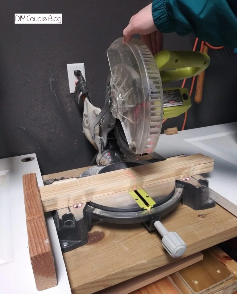 using a miter saw to cut the wood to make a cheap frame for printable nursery wall art