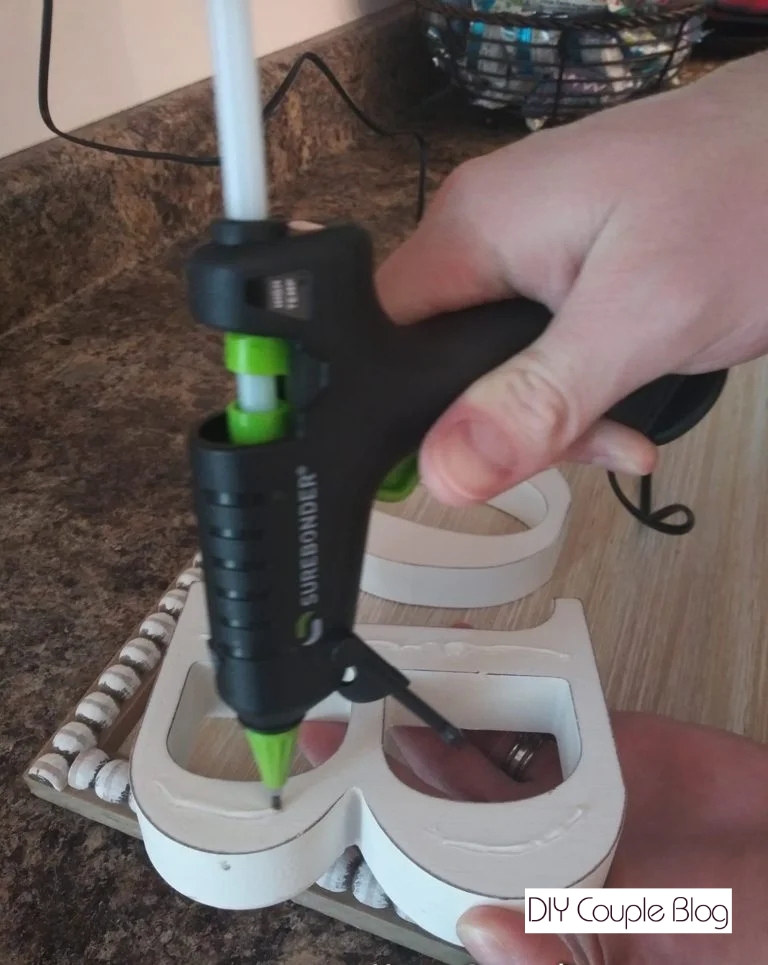 gluing down the letters to the sign spelling the word "bows"