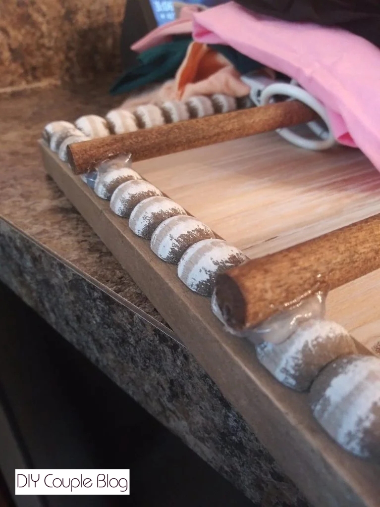 attaching two wooden dowel rods to a decorative wood sign