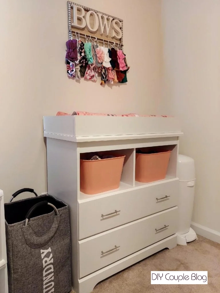 farmhouse headband and bow holder hanging in baby girls' room above changing table with an assortment of headbands hanging