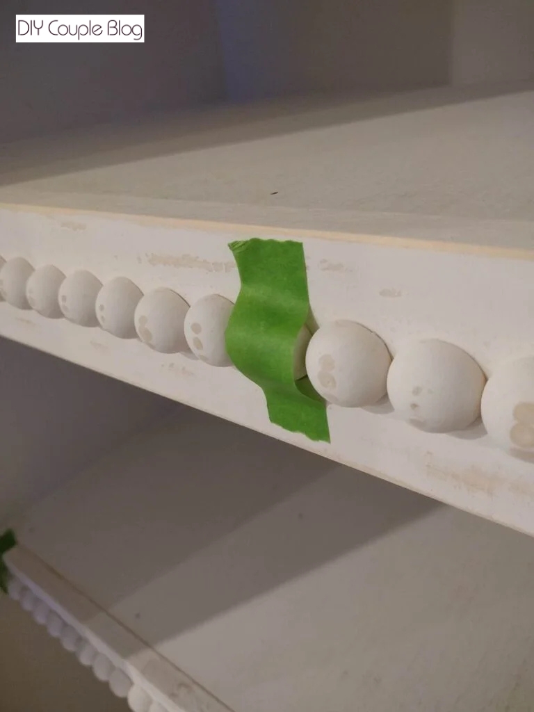 taped wood bead while the glue dries on DIY pantry shelving