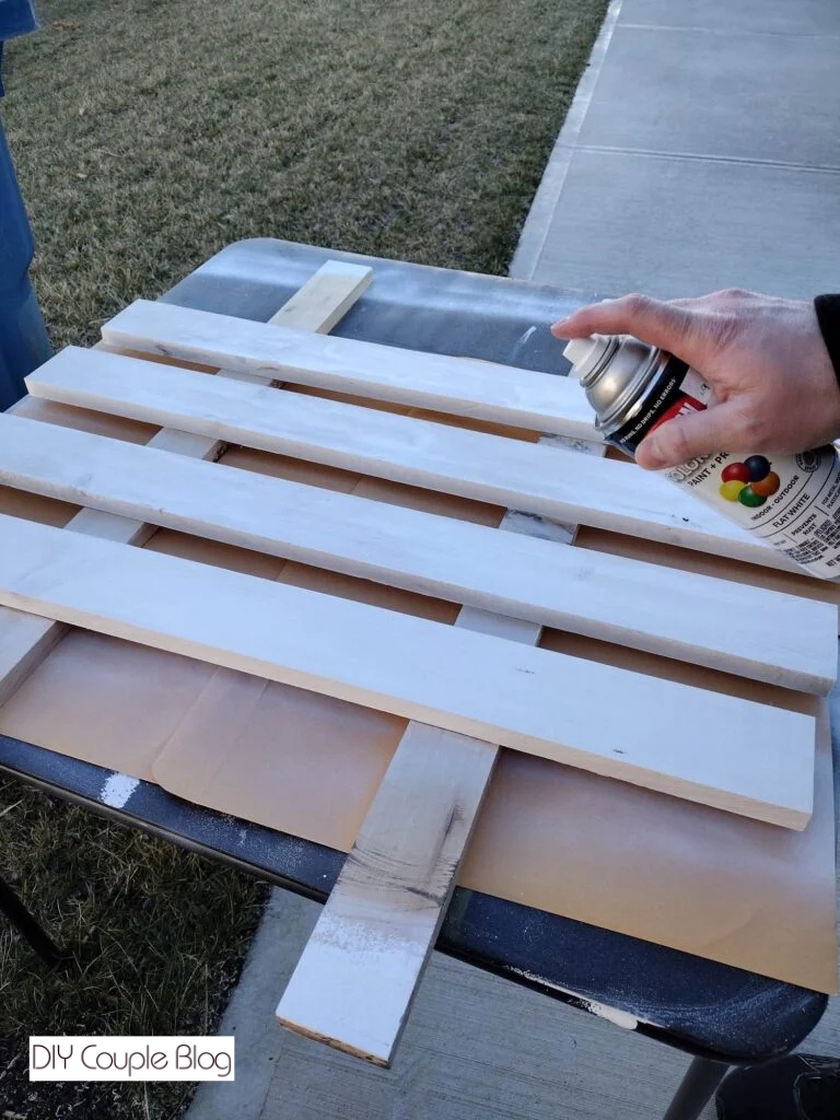 spray painting front shelf boards white for DIY pantry shelving