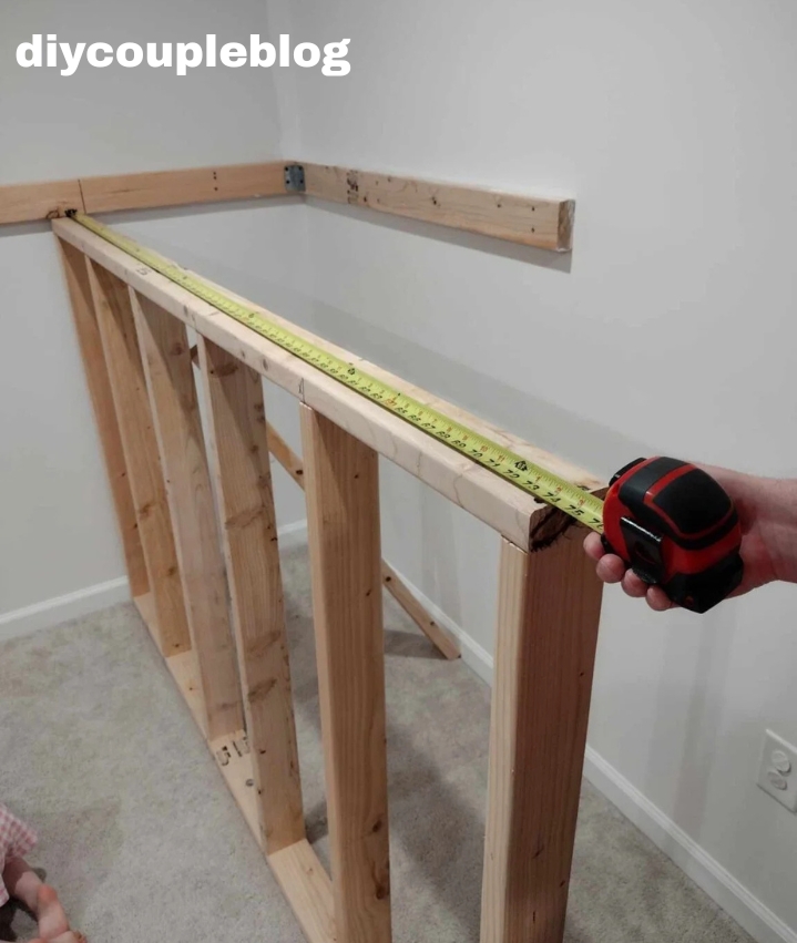 homeowner measuring for the top piece of wood to jungle gym platform