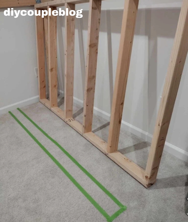 wood frame walls with tape marked out in the carpet of where it will go