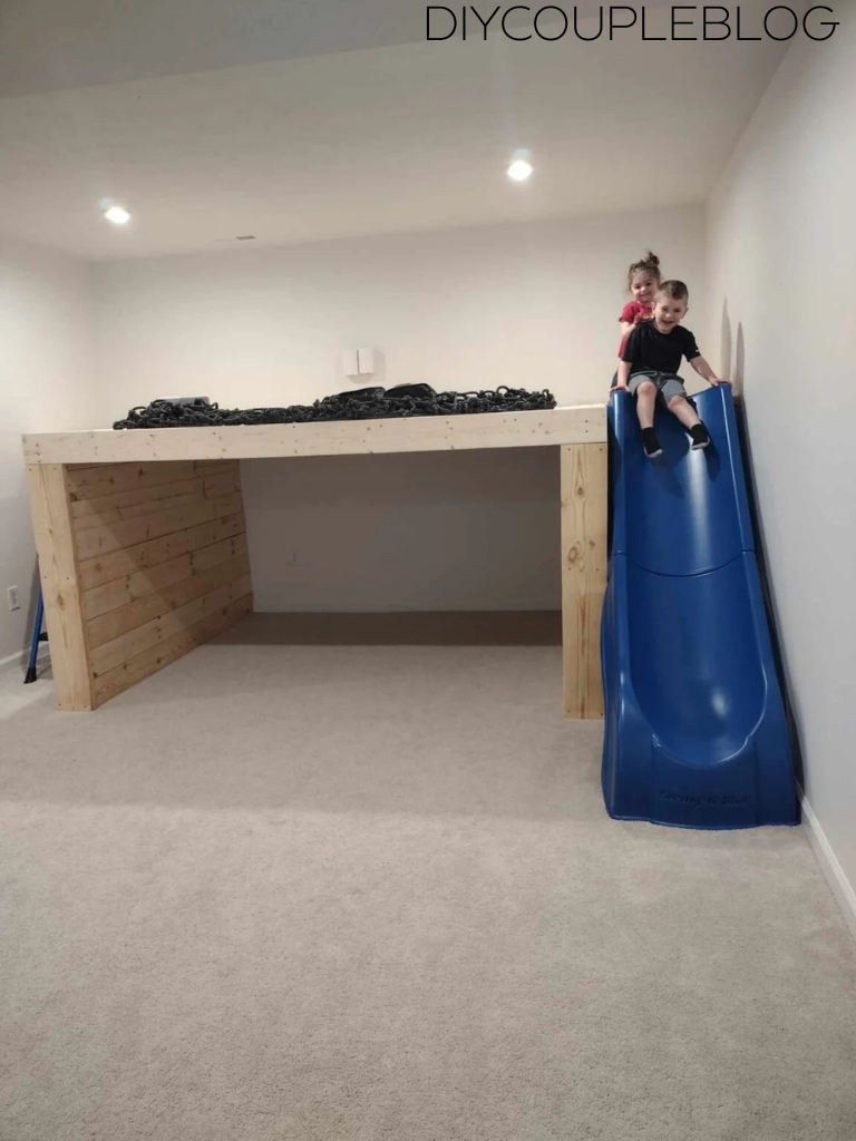 kids taking a turn sliding down a blue indoor slide 