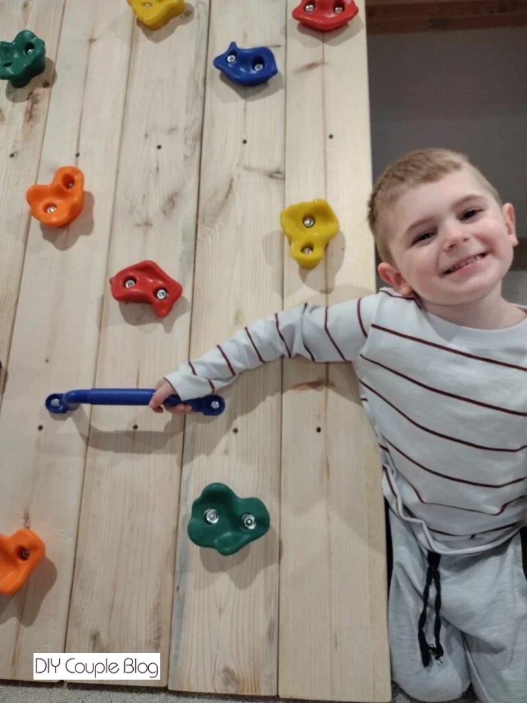 child posing with climbing rock platform and holding handles
