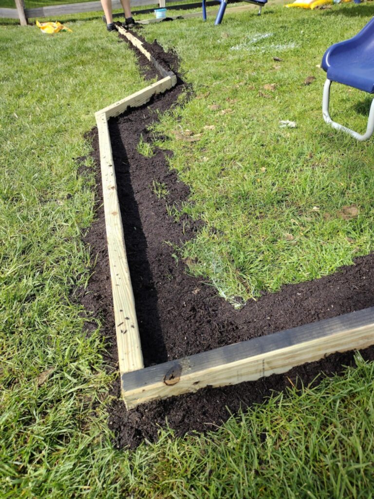 adding dirt to fill the gaps  for our diy playground in our backyard