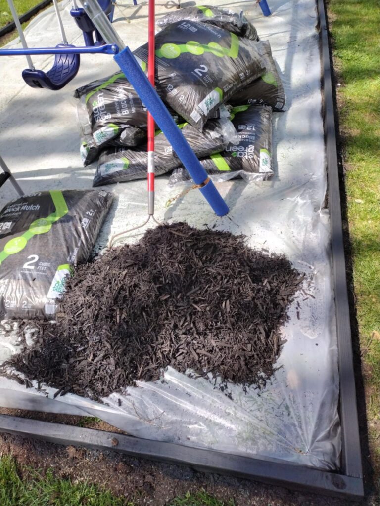 getting ready to spread black mulch inside the playground area border