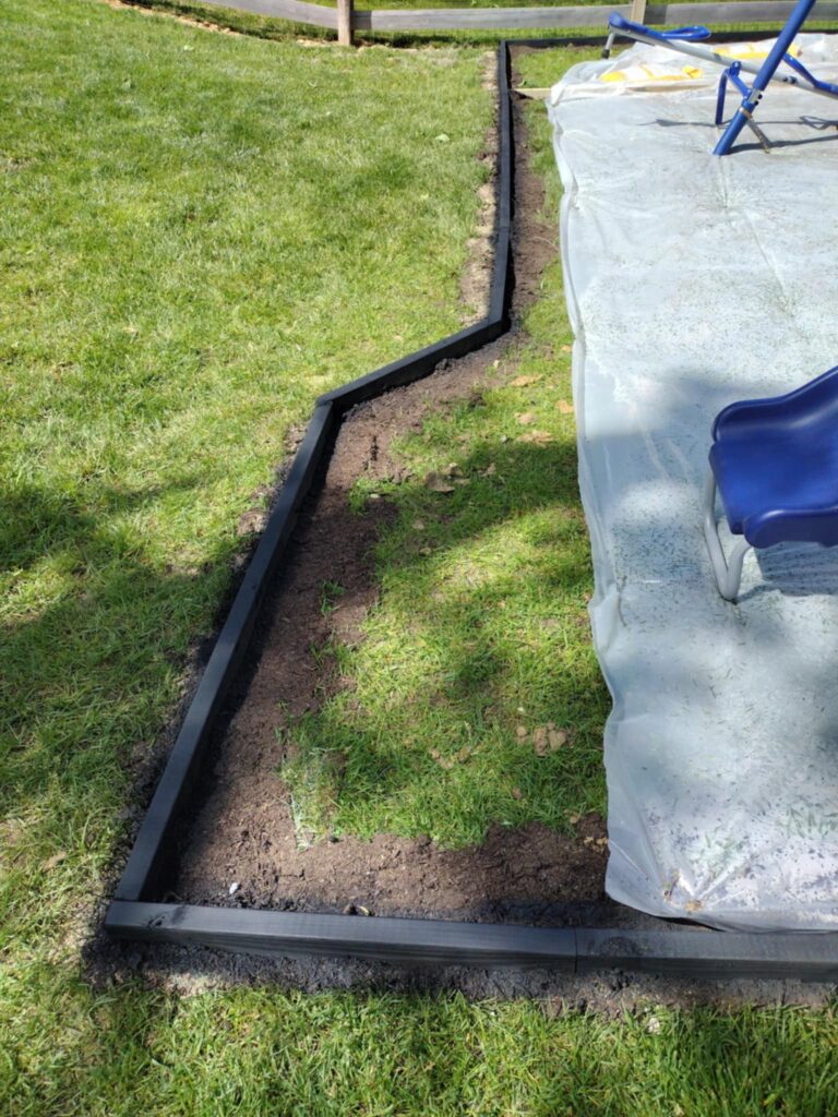 staking down the plastic the rest of the way inside the playground area 