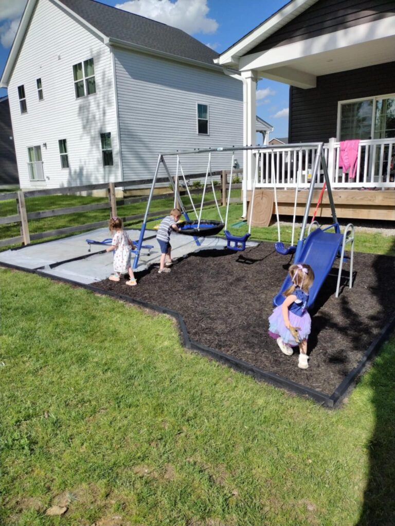 kids playing on a playground with black mulch and black border around the edge