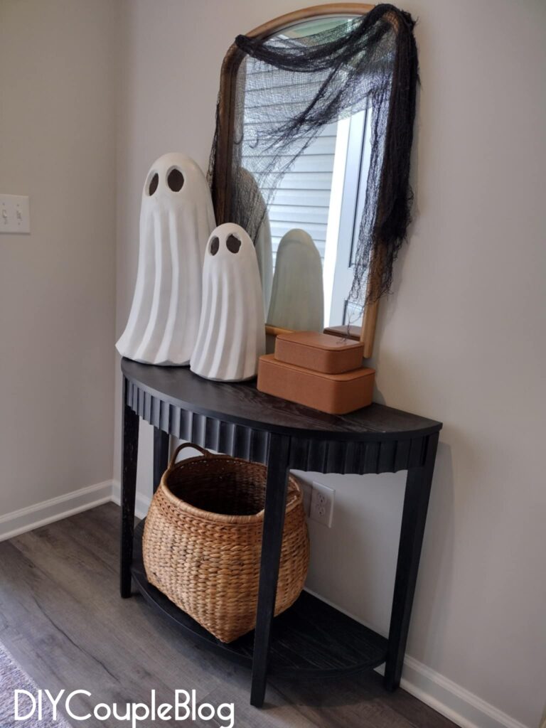 halloween entryway with ghosts, creepy cloth draped over mirror and a black console table. 