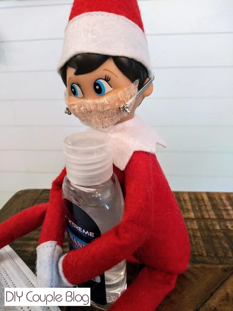 Sick Christmas elf with DIY face mask and holding hand sanitizer 